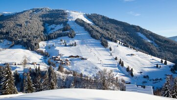 Snowy mountain scenery with ski slopes, lifts and huts near the forest in Dienten