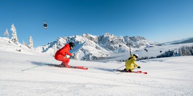Zwei Skifahrer auf frisch präparierter Piste mit Blick auf das verschneite Hochkönig-Massiv | © Hochkönig Tourismus GmbH