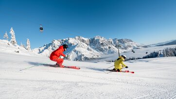 Zwei Skifahrer auf frisch präparierter Piste mit Blick auf das verschneite Hochkönig-Massiv | © Hochkönig Tourismus GmbH