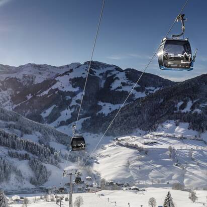 Gondeln der Sonnbergbahn fahren über verschneite Hänge bei Maria Alm in der Wintersonne | © www.felsch-foto.at