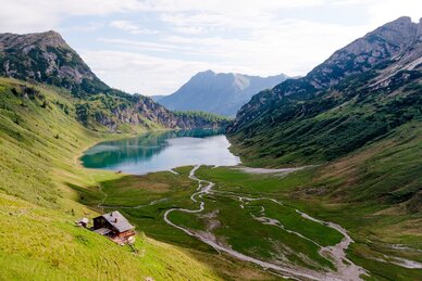 Blick auf einen klaren Bergsee mit Alm, Wiesen und Wasserläufen in einem von Bergen eingerahmten Hochtal | © Wagrain-Kleinarl Tourismus